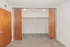 Spacious walk-in closet with elegant wooden sliding doors and plush carpeting, providing ample storage space and a touch of luxury.