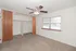 Inviting bedroom with plush carpet, ample closet space, sliding wooden doors, and a large window providing natural light.