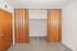 Inviting bedroom with sliding wooden closet doors offering ample storage space and plush carpeting.
