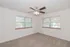 Bright and airy bedroom with large windows, soft carpet, and a stylish ceiling fan.