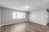 Bright and spacious living room with elegant hardwood floors, large windows, and a cozy air conditioning unit.