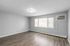 Bright and airy room with modern wood flooring, large window, and wall air conditioning in a stylish apartment.