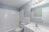 Bright, modern bathroom with elegant white tiles, sleek vanity, and contemporary light fixtures.