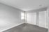 Bright and inviting bedroom with soft gray walls, plush carpeting, and ample natural light from a large window.