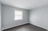 Bright, spacious room with soft gray walls and a large window, perfect for personalization and comfort.