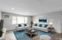 Elegant living room with modern furniture, a plush blue area rug, and abundant natural light streaming in.