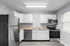 Modern kitchen with sleek stainless steel appliances, bright cabinetry, and a spacious countertop. Natural light fills the room from a large window, highlighting the elegant design.