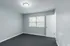 Bright, neutral-toned room with new carpeting and large window letting in natural light, ideal for flexible living space.