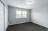 Bright and spacious bedroom with fresh gray walls, featuring ample natural light and sleek closet doors.