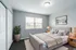 Inviting bedroom featuring a plush bed with layered pillows, soft ambient lighting, and a large window flooding the space with natural light.