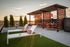 dining tables under pergola and chaise chairs on green turf