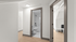Modern apartment hallway featuring sleek wooden flooring, a bathroom with elegant fixtures, and an inviting room entrance.