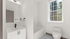 Bright and modern bathroom featuring a sleek white vanity, stylish black fixtures, and a sunlit window.
