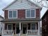 Charming red townhouse with inviting front porches and large windows, ideal for cozy living.