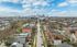 Charming aerial view of a vibrant neighborhood with tree-lined streets and a bustling city skyline in the distance.