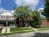 Charming suburban duplex with inviting front porches and lush greenery under a bright blue sky.