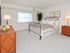 Carpeted bedroom with a large bed, nightstand and dresser at Valley Stream Apartments in Lansdale, PA.