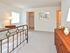 Carpeted bedroom with a walk-in closet furnished with a large bed, nightstand and dresser at Valley Stream Apartments in Lansdale, PA.