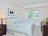Carpeted bedroom with a large bed, nightstand and dresser at Valley Stream Apartments in Lansdale, PA.