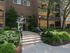 Entrance to brick and yellow apartment building with stairs and well maintained landscaping
