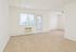Model living room with large windows and in-wall A/C unit at Norriton East Apartments in East Norriton, PA.