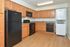 Model kitchen with wood-style flooring, wooden cabinets and modern appliances at Willow Run Apartments in Willow Grove, PA.