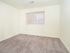 Sunny bedroom with large window and plush carpet flooring