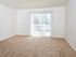 Large living room with carpet floors and sliding glass doors leading out to private balcony
