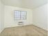Carpeted bedroom with a large window and in-wall A/C unit at Woodland Plaza Apartments in Wyomissing, PA.
