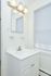 White bathroom with overhead lighting and sink with vanity