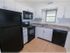 Kitchen with tile floor, white cabinets, and black appliances in apartment for rent in Reading, PA