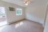 Carpeted living room with a sliding patio door, ceiling fan and in-wall A/C unit at Oak Forest Apartments in Reading, PA.