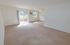 Carpeted living room with a sliding patio door, ceiling fan and in-wall A/C unit at Oak Forest Apartments in Reading, PA.