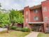 Red brick apartment building with leafy tree and sculpted bushes