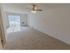 Carpeted living room with sliding patio door, in-wall A/C unit and a ceiling fan at Mayflower Crossing Apartments in Wilkes-Barre, PA.