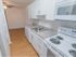Galley kitchen with hardwood floors and white cabinets and appliances