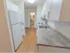 Galley kitchen with hardwood floors and view in to bathroom at end of hall