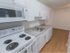 Hardwood flooring in apartment kitchen with white cabinets and appliances