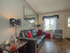 Furnished apartment living room with large window, exterior entrance, and hardwood flooring