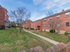 Grassy courtyard with sidewalks outside of brick residential buildings at Evergreen Club apartments for rent