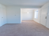 Spacious living area into dining room with white walls and carpeting