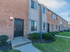 Brick exterior of townhome complex with black doors and sculpted bushes