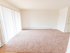 Carpeted living room with large patio door at Polo Ridge apartments in Burlington, NJ.