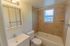 Model bathroom with vanity sink, toilet and tiled tub shower at Paoli Place Apartments in Paoli, PA.