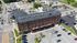 Aerial view of a historic red brick apartment building surrounded by ample parking and vibrant urban landscape.