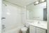 Pristine bathroom with a spacious bathtub, elegant white vanity, and a large mirror creating a bright, inviting space.