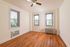 Bright and inviting room with rich hardwood floors, three large windows, and a stylish ceiling fan, perfect for a cozy living space.