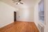 Bright and airy room with wooden floors, ceiling fan, and ample natural light from large window, perfect for a cozy urban retreat.