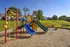 Vibrant children's playground with colorful slides and climbing structures, set in a well-maintained grassy area, perfect for family fun.