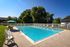 Inviting outdoor pool surrounded by lush greenery and comfortable lounge chairs, perfect for relaxation and leisure.